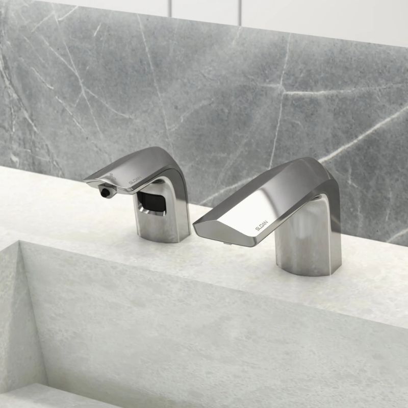 Sloan automatic faucet and soap dispenser in chrome finish, installed on a solid surface sink with a gray marble wall in the background.