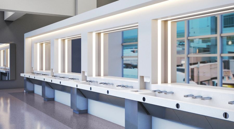 Modern sink area in a transportation terminal, featuring a minimalist design, white solid surfaces, and architectural lighting.