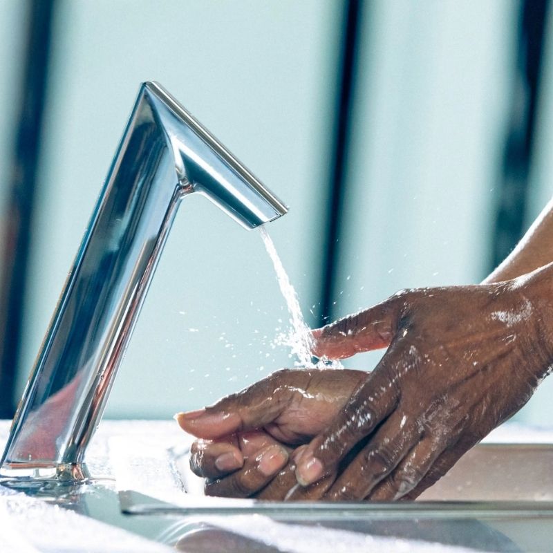 Hands washing under Sloan chrome touchless faucet