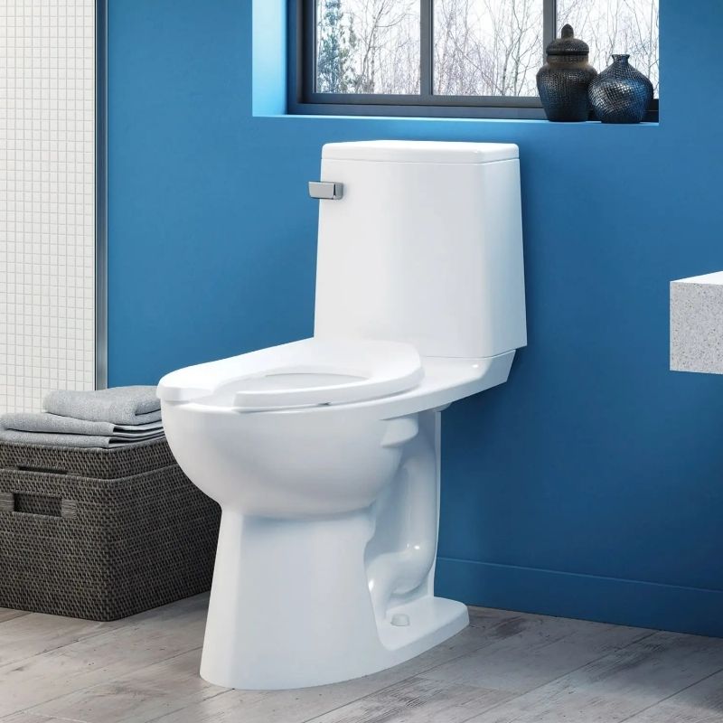 White pressure-assisted toilet installed in a modern blue bathroom, showcasing Sloan’s clean and efficient design.