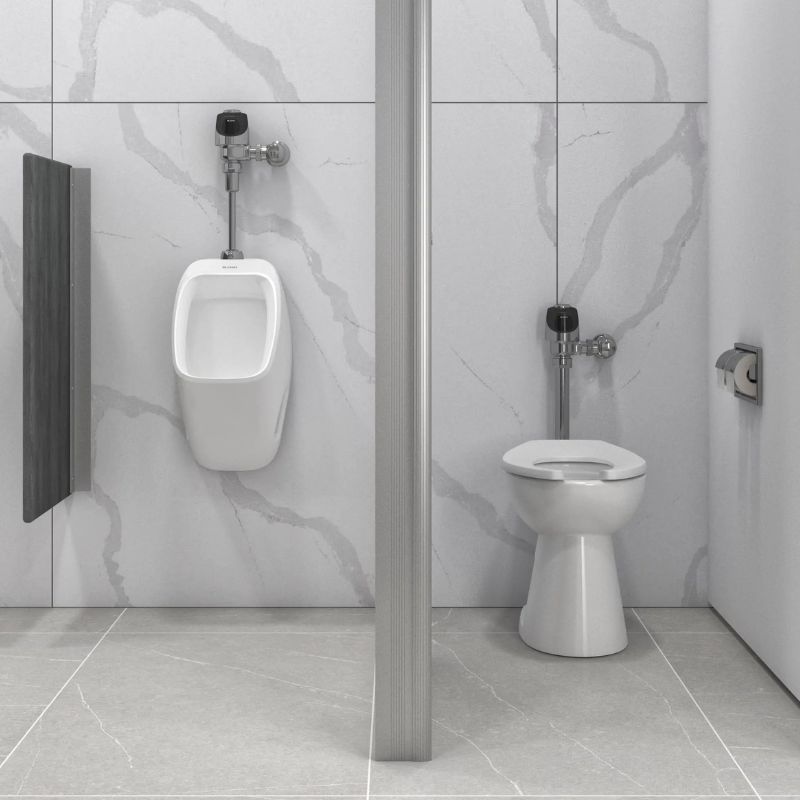 Sloan toilet and urinal with automatic flushometers in polished chrome finish installed in a modern restroom with light gray marble walls.