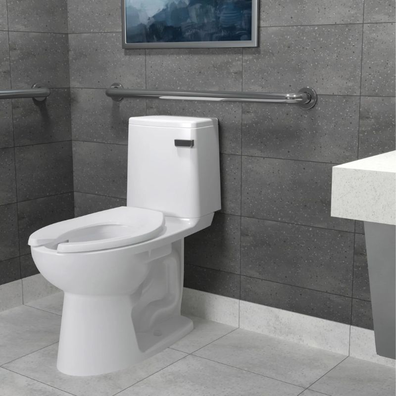 Sloan toilet with tank installed in an accessible restroom featuring gray tiled walls, metal grab bars, and light ceramic flooring.