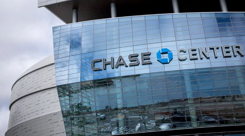 Exterior view of the Chase Center in San Francisco, featuring modern architecture and a distinctive curved glass façade reflecting the urban surroundings.