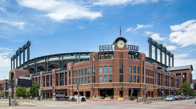 Coors Field, the iconic baseball stadium located in Denver, Colorado, home of the Colorado Rockies of Major League Baseball (MLB). Its red brick façade blends classic architecture with modern steel framing, reflecting the industrial character of Denver’s LoDo district. A large clock and the stadium’s name sign stand prominently above the main entrance, serving as distinctive architectural landmarks.