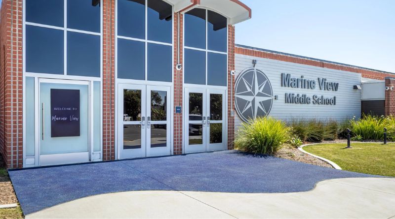 Main entrance of Marine View Middle School featuring modern architecture, red brick, and the Ocean View School District compass emblem symbolizing direction and learning.
